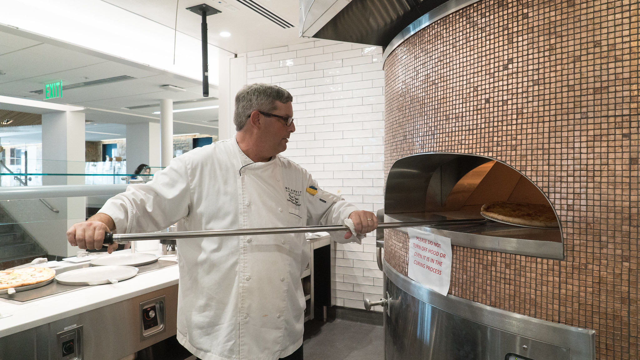 A chef takes a pizza out of a wood fire oven